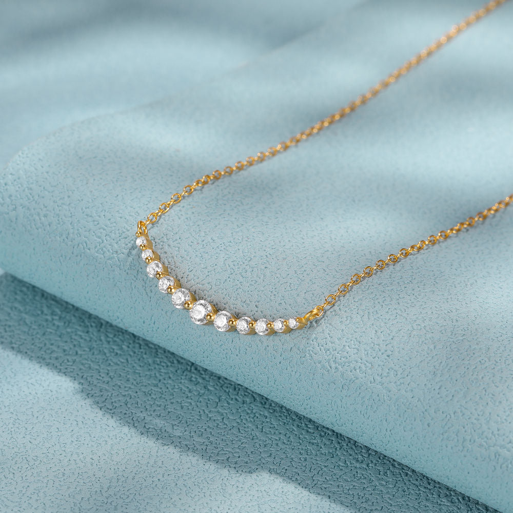 Gold necklace with small pearls on a light blue fabric background