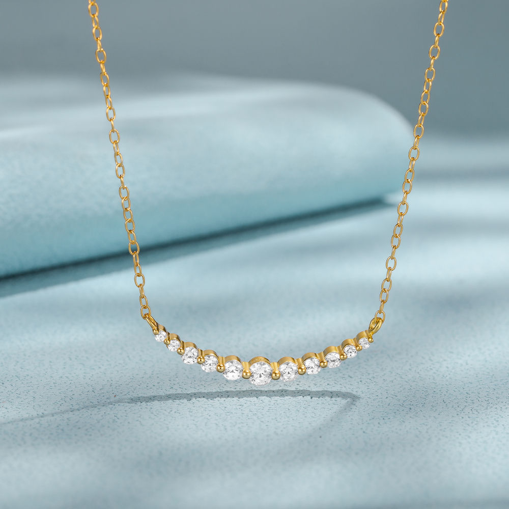 Gold necklace with small diamonds on a light blue fabric background