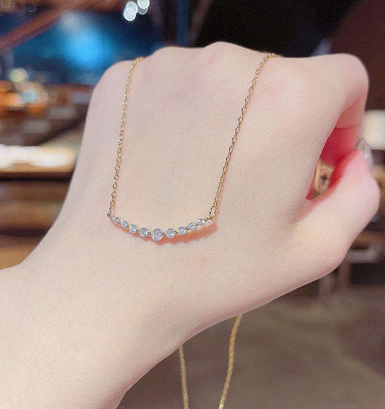 Gold necklace with small diamonds on a hand against a blurred background