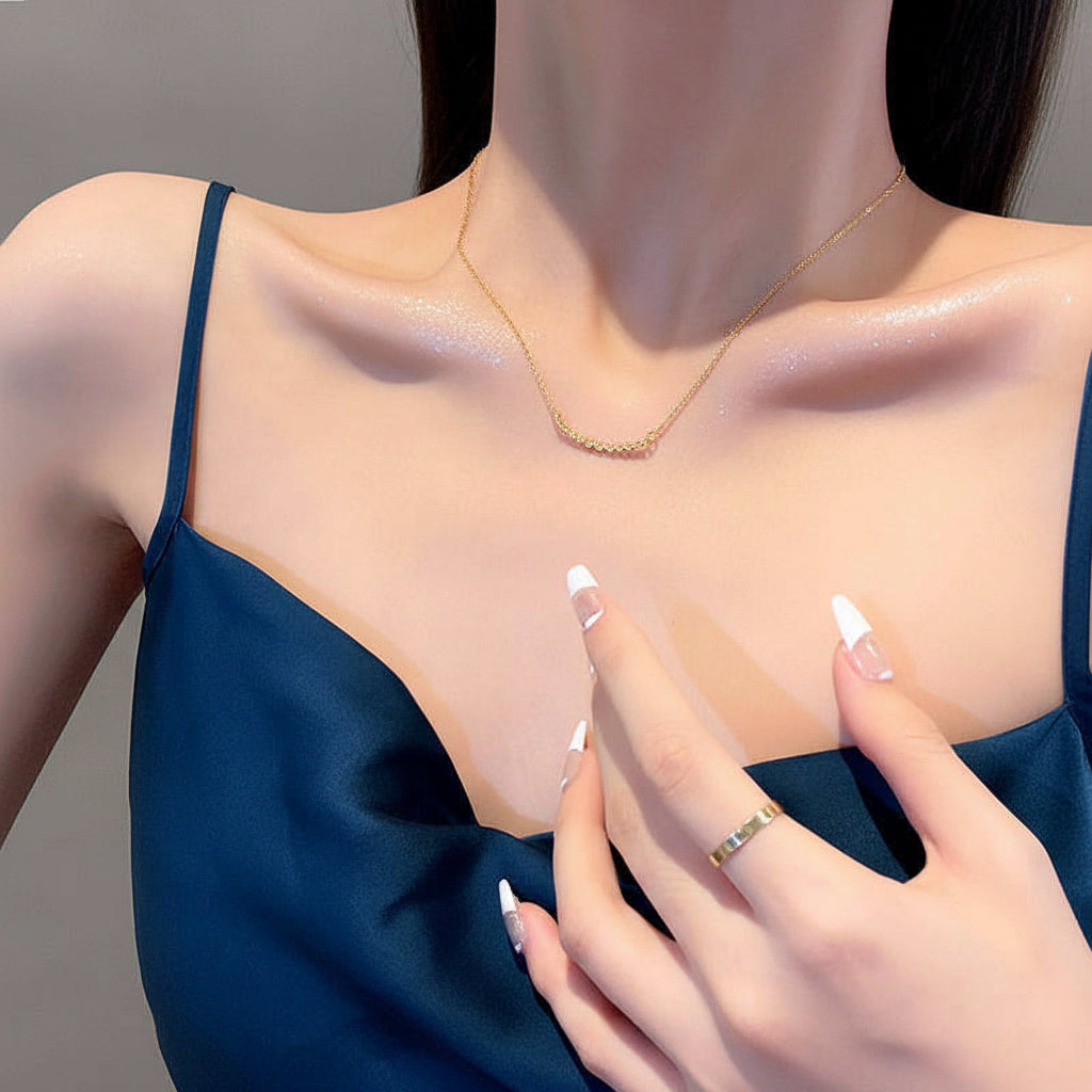 Woman wearing a delicate necklace with a plain background