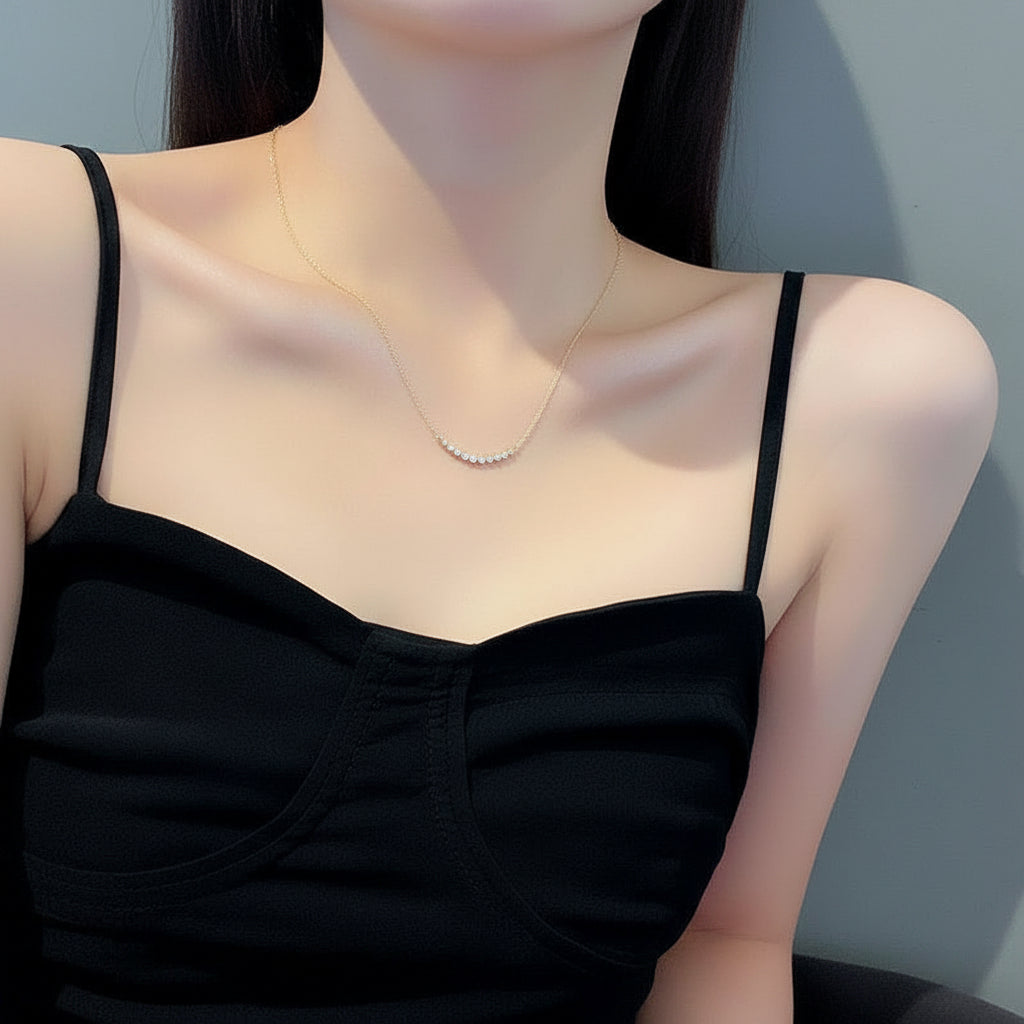 Woman wearing a gold chain necklace and black top against a neutral background