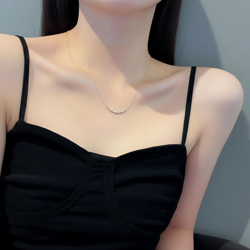 Woman wearing a gold chain necklace and black top against a neutral background