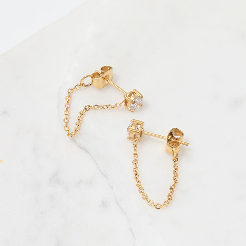 Gold chain earrings on a light background