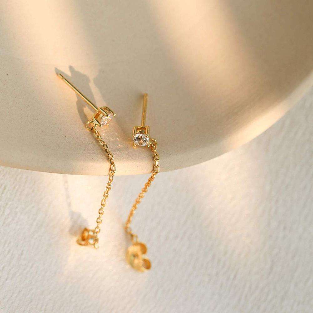 Gold earrings with chain details on a neutral background
