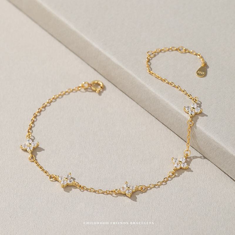 Gold bracelet with floral designs on a light beige background