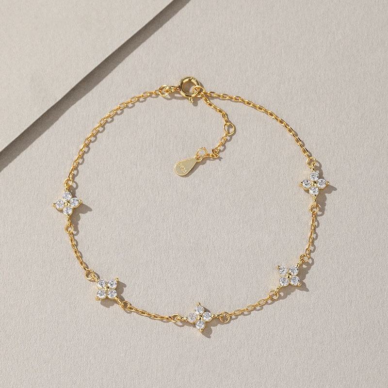 Gold bracelet with floral charms on a light beige background