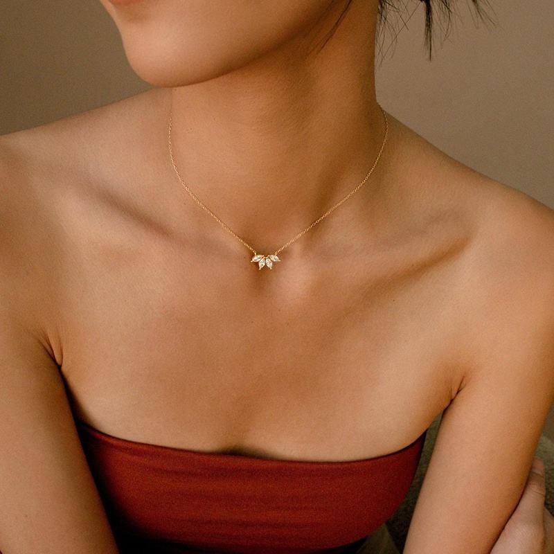 Necklace with a delicate flower pendant worn by a person against a neutral background