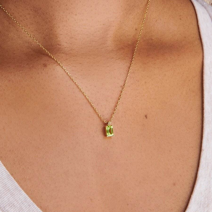 Gold necklace with a green pendant on a person's neck