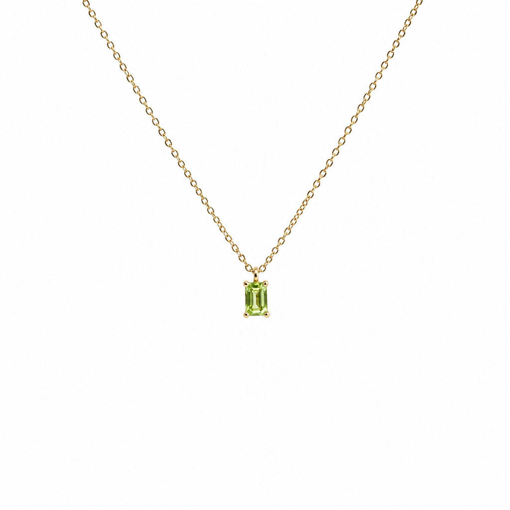 Gold necklace with a green gemstone pendant on a white background
